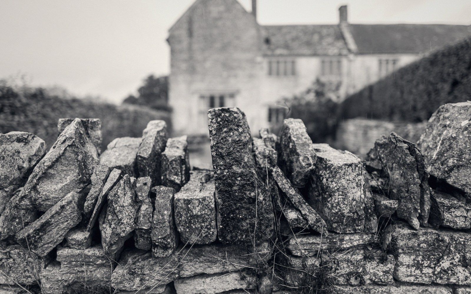 Dry stone wall with upright capping stones stands before a stone farmhouse