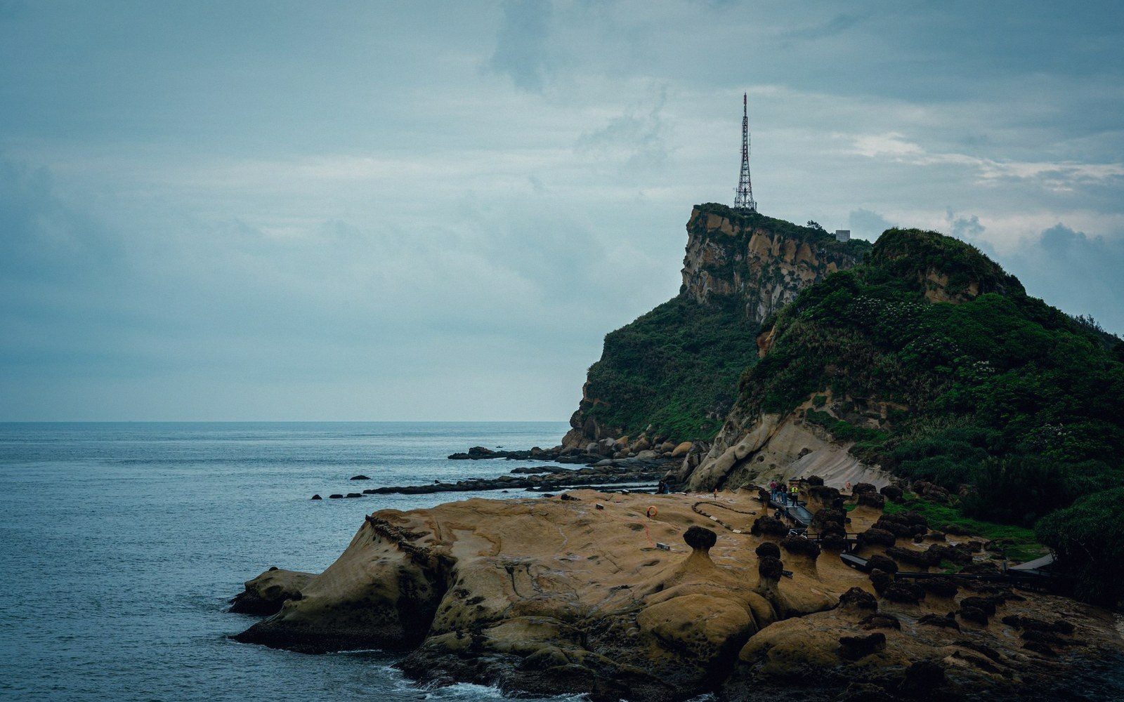 Rocky coastal headland with mushroom-shaped rock formations and a communications tower on top