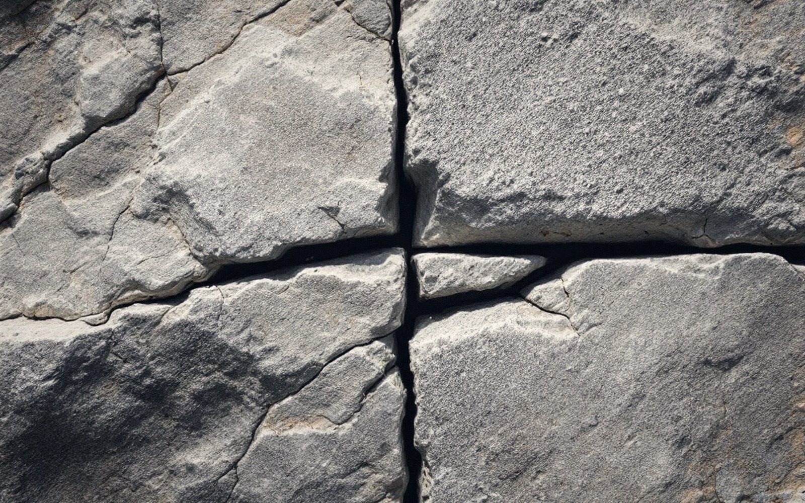 Close-up of a granite block split along intersecting cracks radiating from a central point