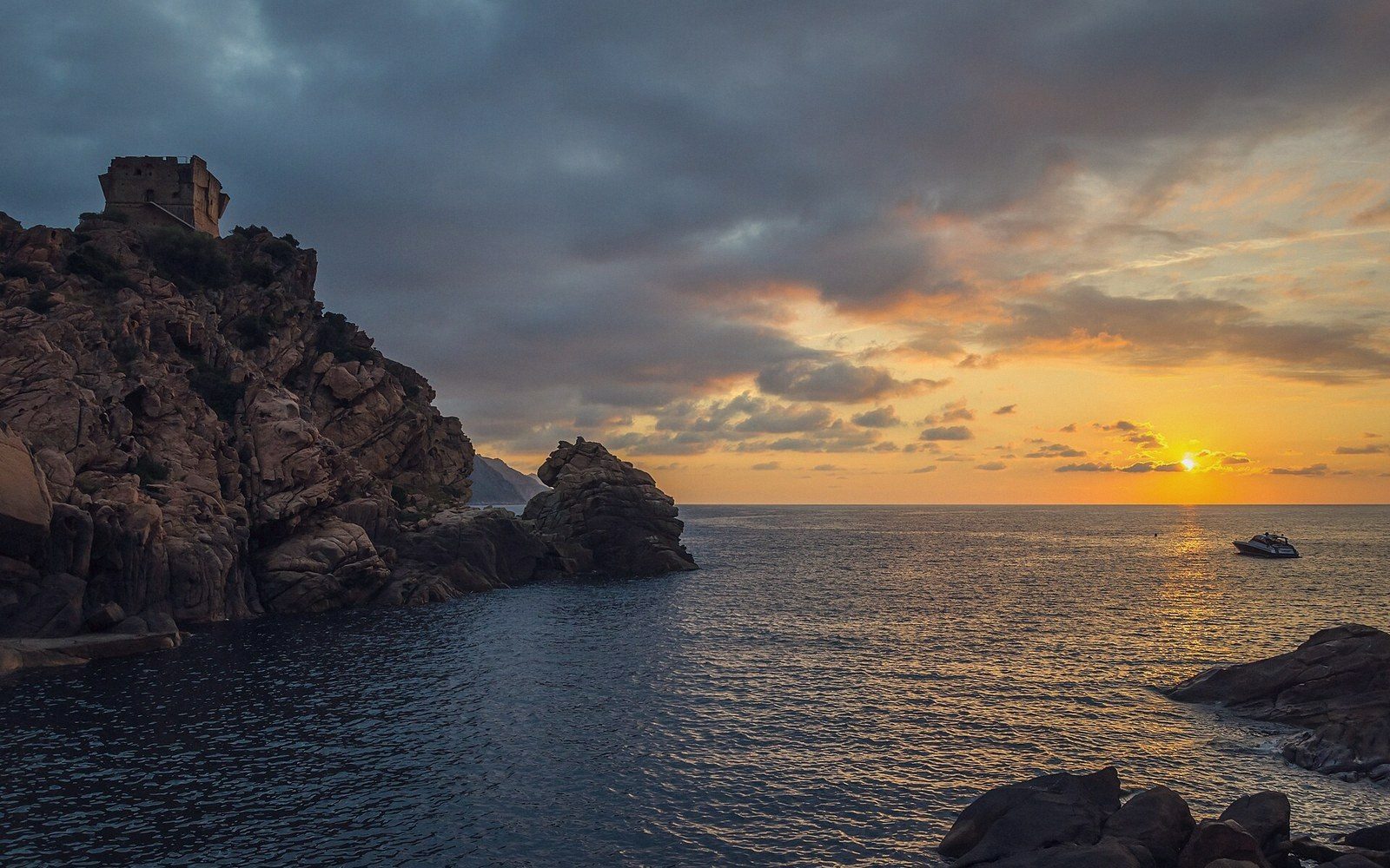 A round stone watchtower on a headland with the sea behind